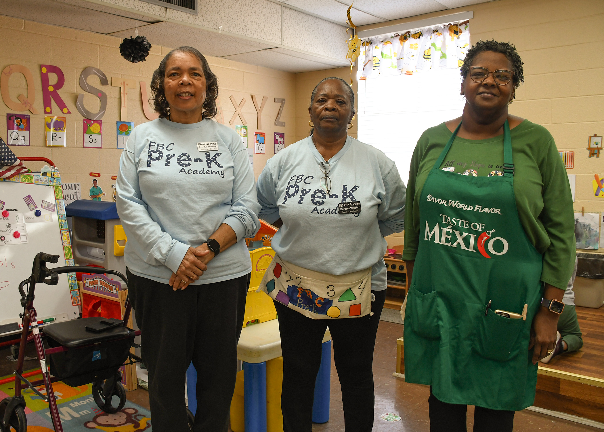 Three African American preschool teachers standing in a preschool classroom.