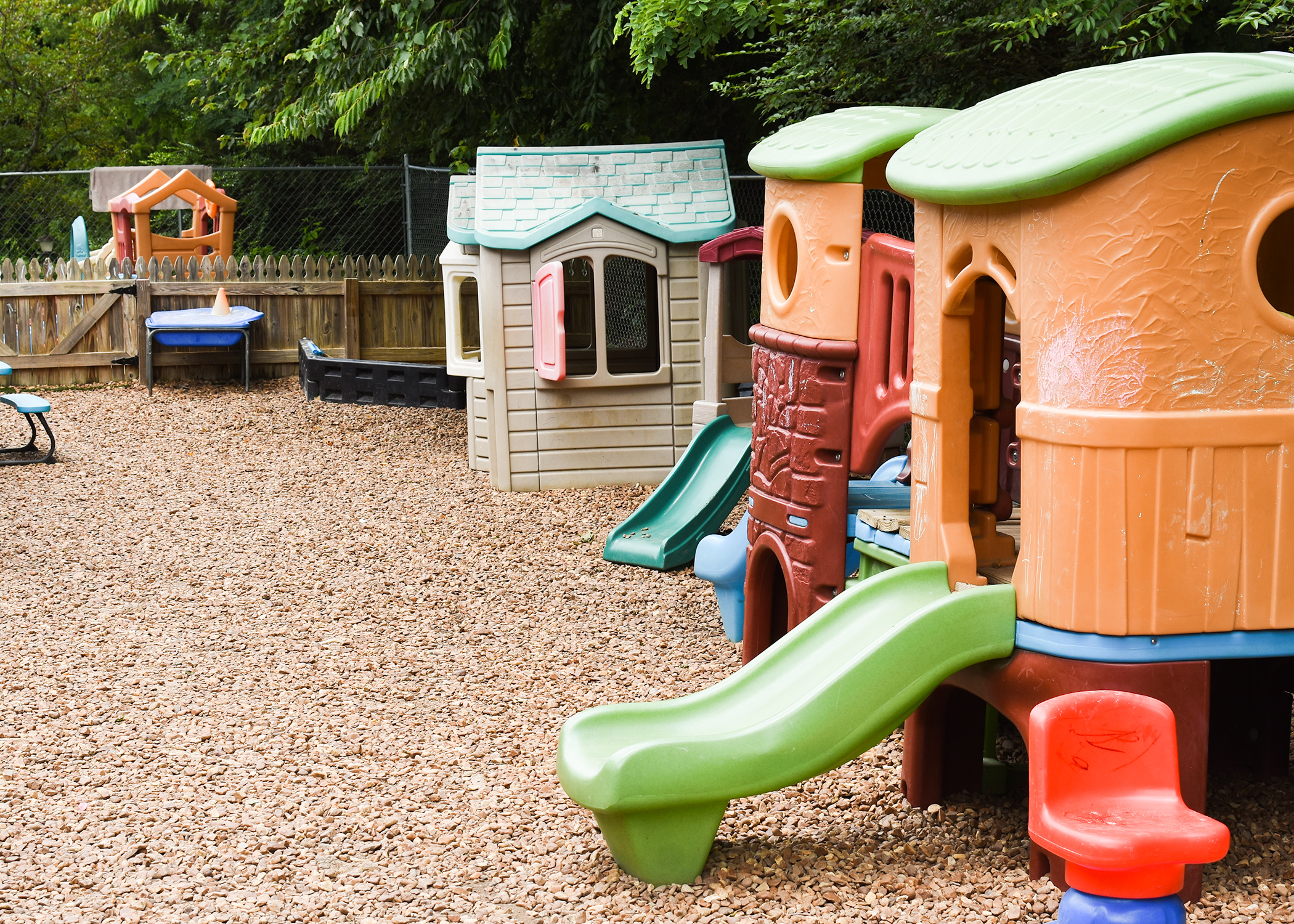 A playground at a child care center. Plastic play places sit in pea gravel.